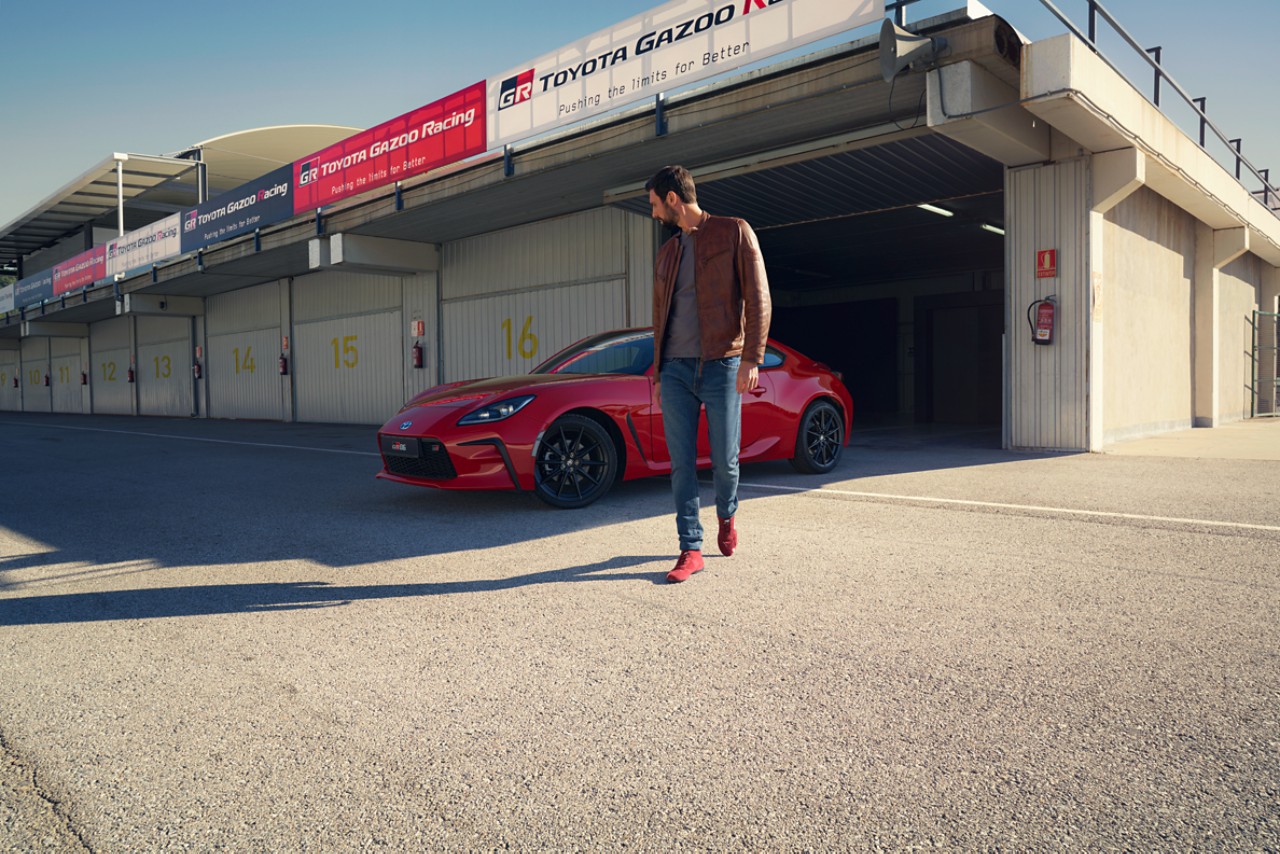 toyota-gr86-exterieur-zijkant-rood-met-man-ervoor