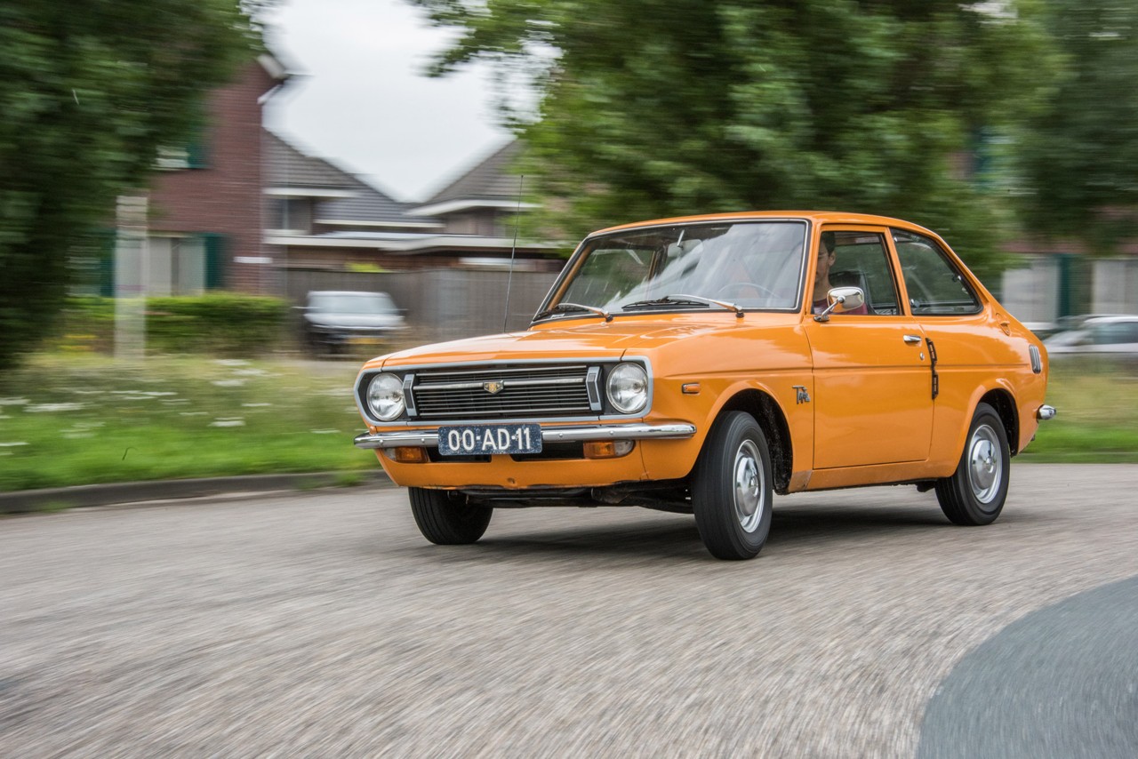 Toyota 1000, exterieur, schuin voor, oranje, rijdend op rotonde