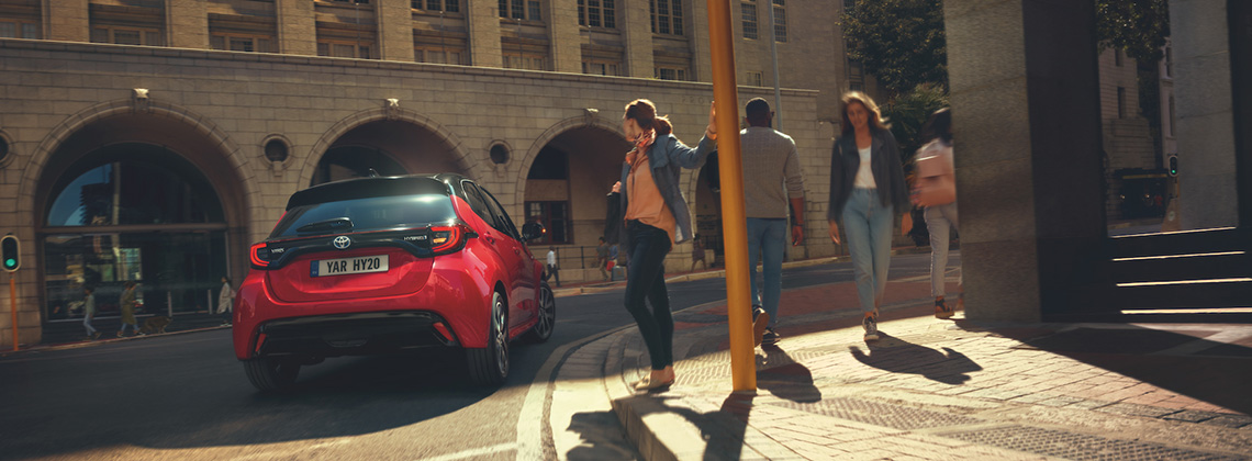 Toyota Yaris Hybrid, exterieur, rood, rijdend langs groep mensen